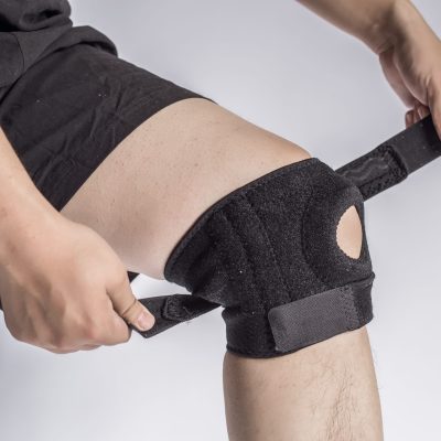 Close-up Of A Man Wearing Knee Brace Over White Background